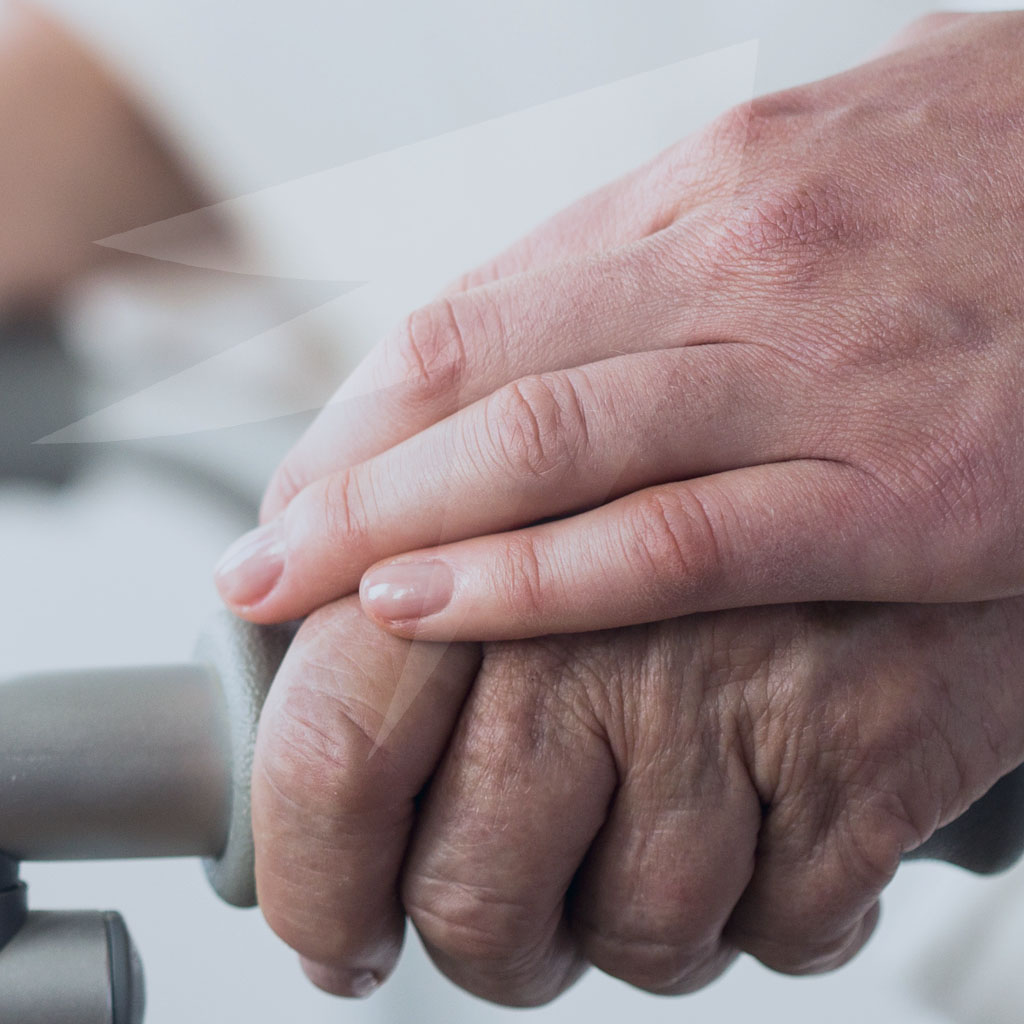 Caregivers hand over senior hand. Learn differences between Medicare and Medicaid.