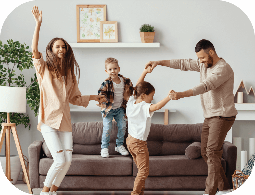 Image of a happy family dancing in their living room.