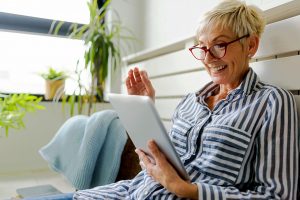 Smiling beautiful senior woman using digital tablet at home researching Medicare Part A