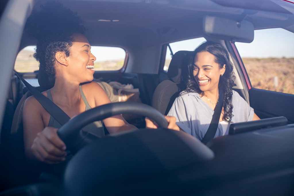 Women smiling in car while driving.