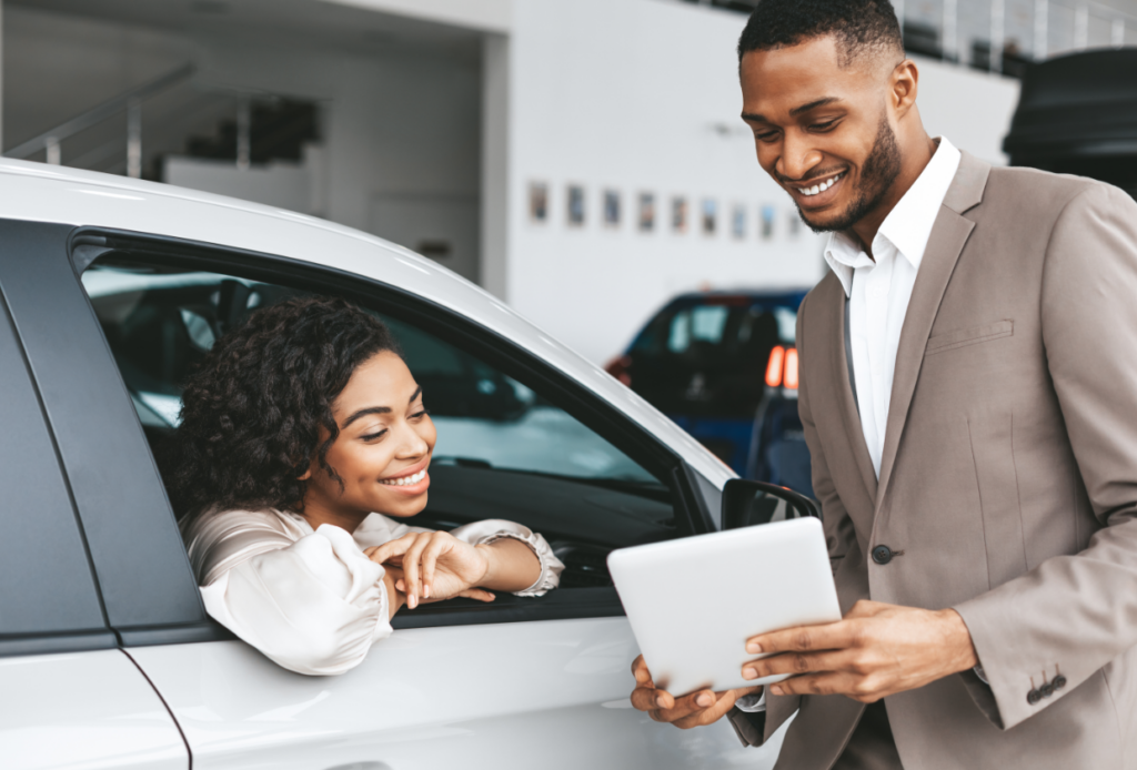 Happy woman reviewing paperwork for her new car at the dealership after being able to get same-day car insurance with the help of Guided Solutions