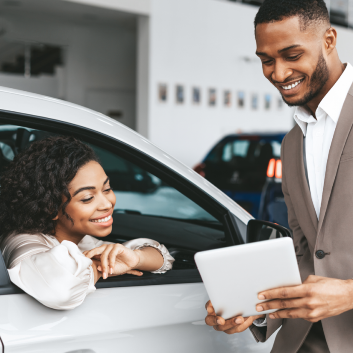 Happy woman reviewing paperwork for her new car at the dealership after being able to get same-day car insurance with the help of Guided Solutions