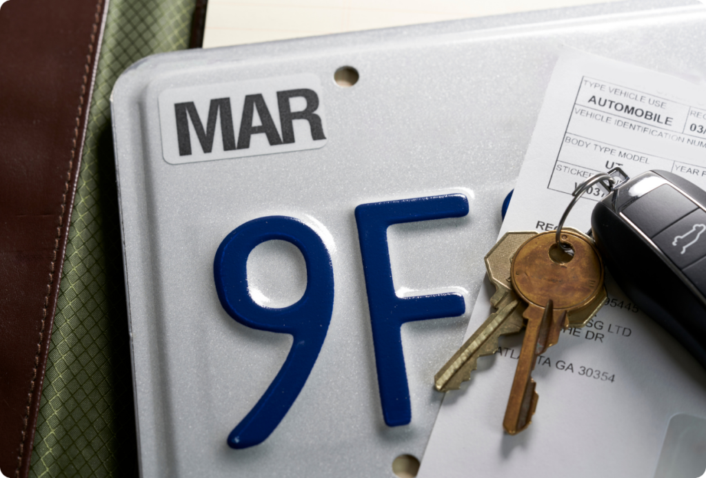 An image showing the process of transferring ownership of a vehicle, including new registration documents, a license plate, and a set of car keys.